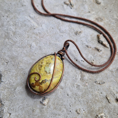 A Green Opal wire wrapped pendant on a brown wax cord, for emotionally healing.