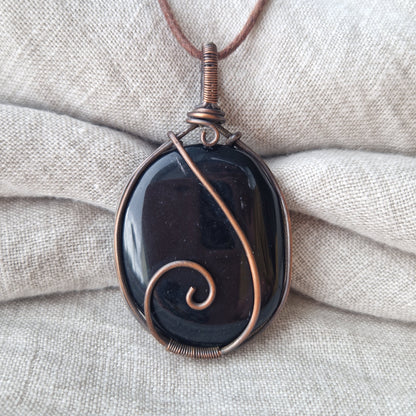 A close up of a memorial healing obsidian crystal pendant