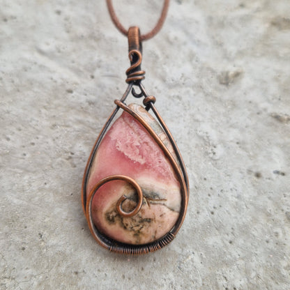 Close up of a rhodochrosite imprinted crystal pendant