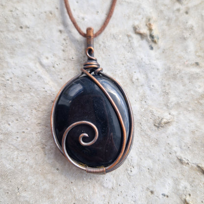 An obsidian crystal wrapped in copper for healing